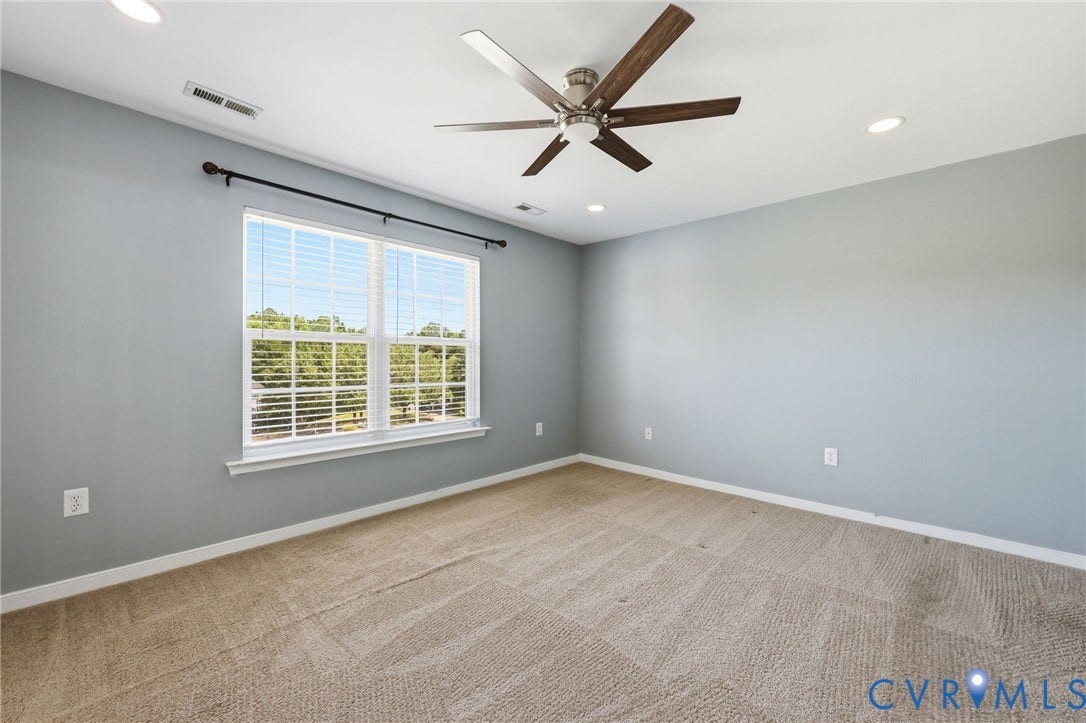 Spacious room featuring neutral carpeting, light gray wall tones, and a multi-pane window with white blinds