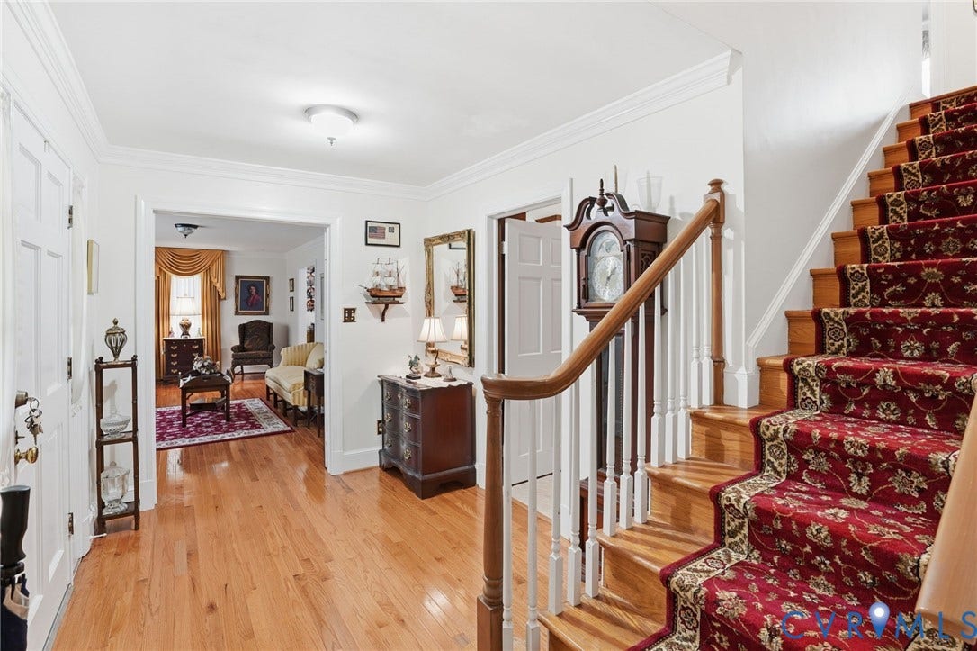 11016 Pridesville Road, Amelia, VA 23002 Foyer featuring wood-finish flooring, a traditional staircase with a red patterned runner, white painted trim, and a wide entryway to an additional room