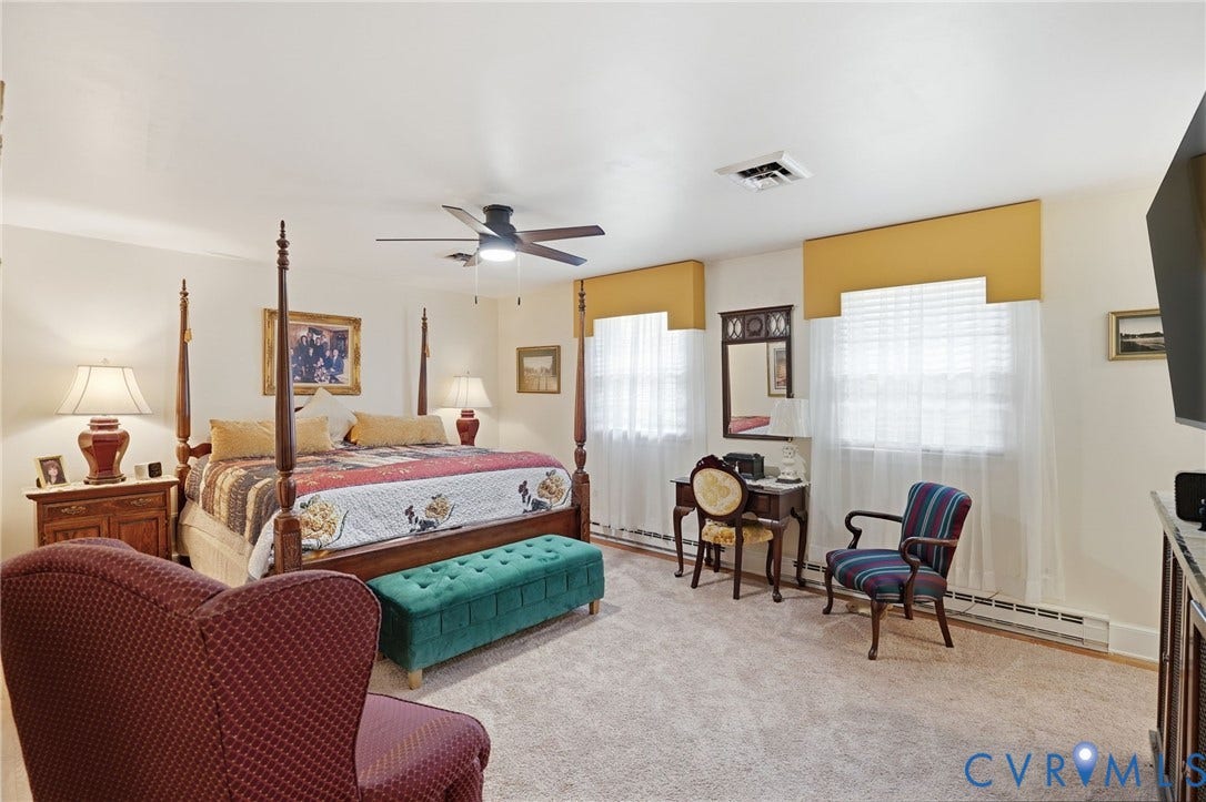 11016 Pridesville Road, Amelia, VA 23002 Carpeted bedroom featuring a ceiling fan with integrated lighting, two windows with valances and sheers, and white baseboard heating