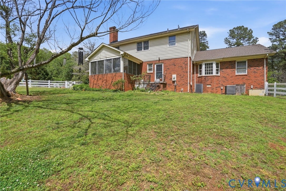 11016 Pridesville Road, Amelia, VA 23002 Rear exterior with brick and siding facade, featuring a screened porch, bay window, and white picket fence