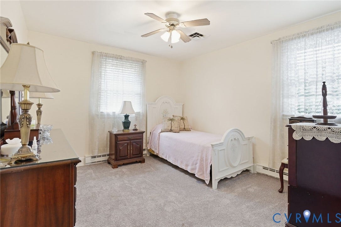 11016 Pridesville Road, Amelia, VA 23002 Carpeted room featuring a ceiling fan, two windows with blinds, baseboard heating, and cream-colored walls