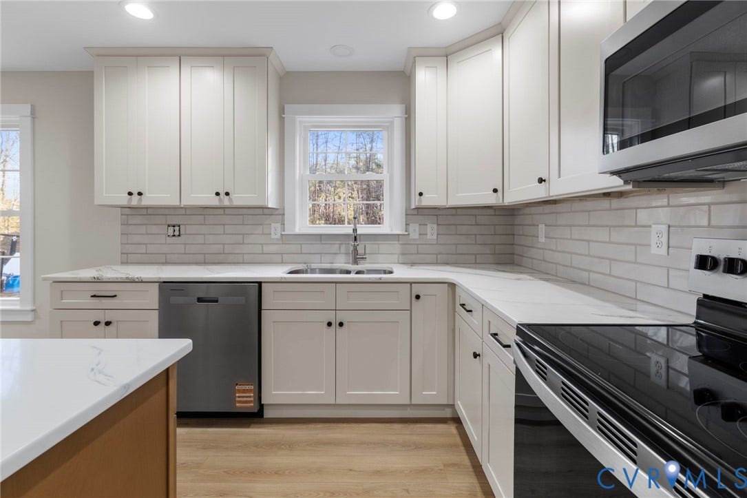 Modern kitchen featuring white shaker cabinetry, stainless steel dishwasher, and matching over-the-range microwave