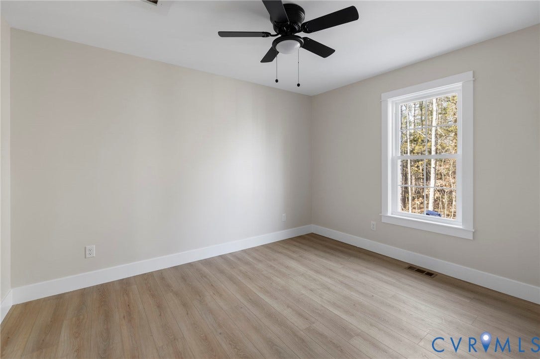 Light-filled room featuring wood-finish flooring, a ceiling fan with integrated lighting, and a double-hung window with white trim