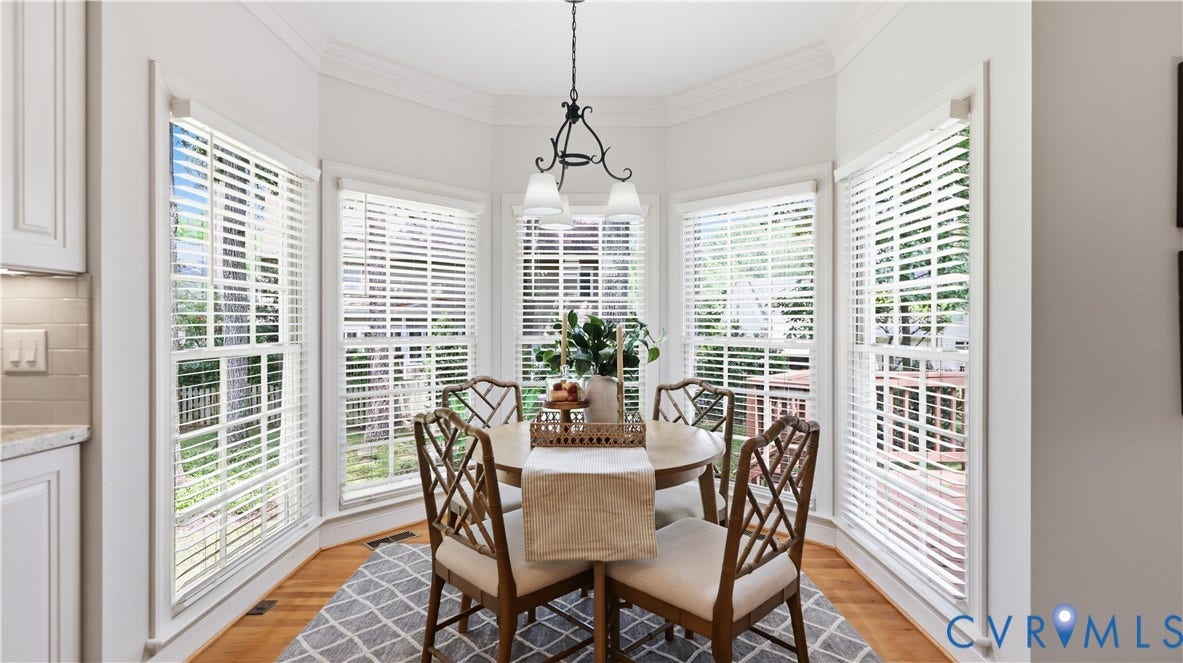 12400 Chadsworth Place, Wyndham, Glen Allen, VA 23059 Bay window dining area featuring wood-finish flooring, an overhead chandelier, crown molding, and white cabinetry
