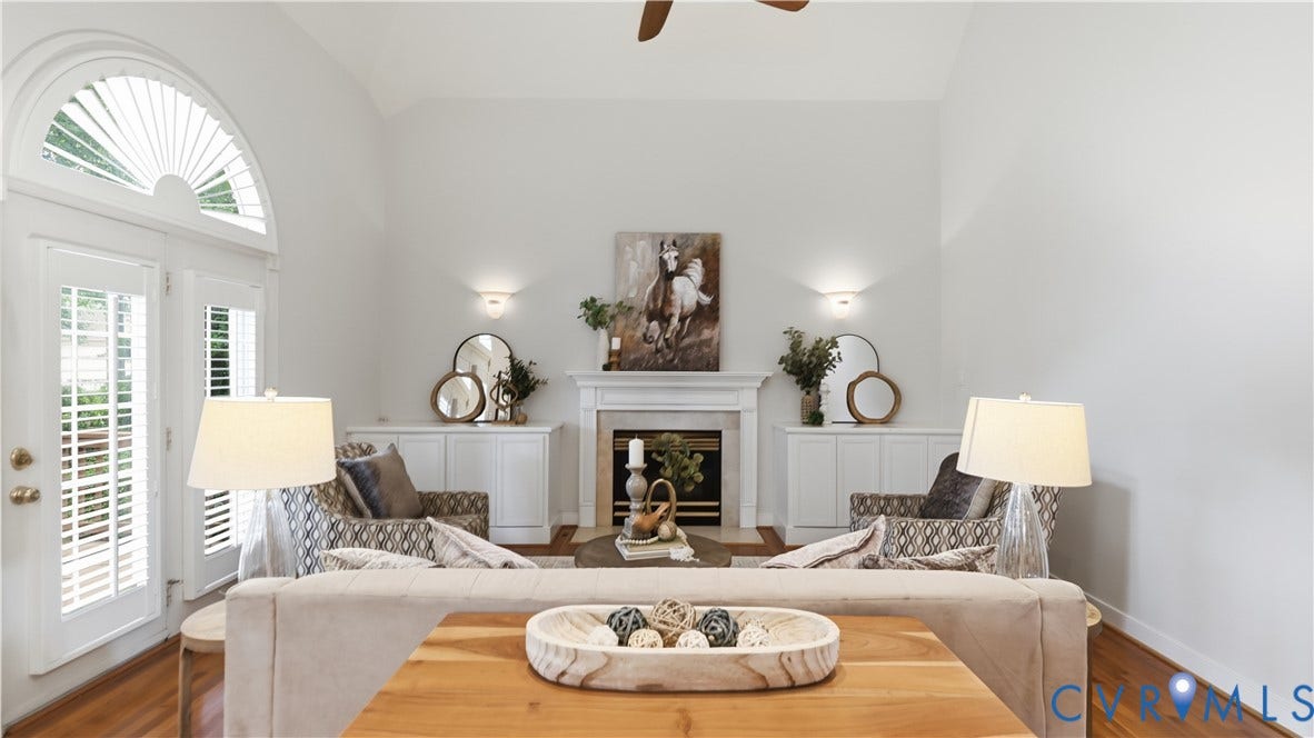 12400 Chadsworth Place, Wyndham, Glen Allen, VA 23059 Living area featuring a fireplace with a white mantel, built-in cabinetry, arched transom window, French doors with louvered shutters, and wood-finish flooring