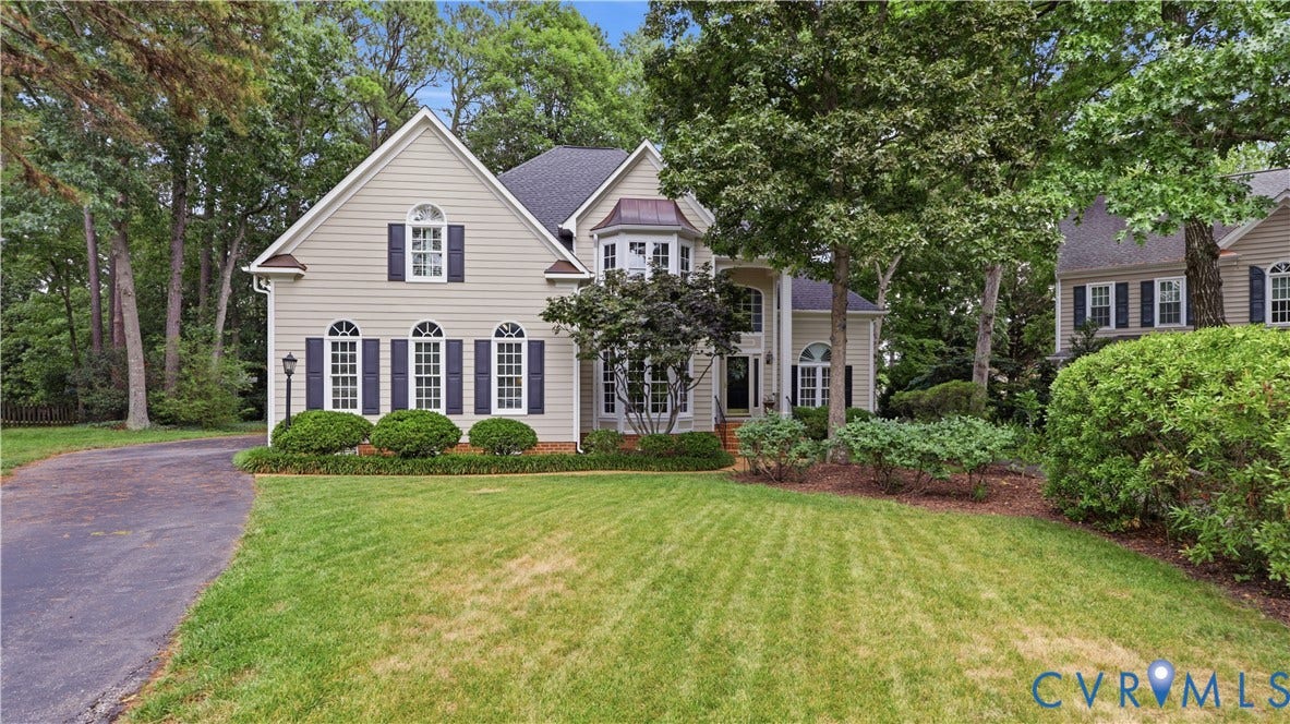 12400 Chadsworth Place, Wyndham, Glen Allen, VA 23059 Traditional-style residence featuring light-colored siding, dark shutters, an arched bay window, a columned portico, and a mature treed setting