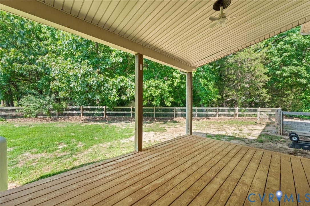 Covered wood deck overlooking a fenced backyard
