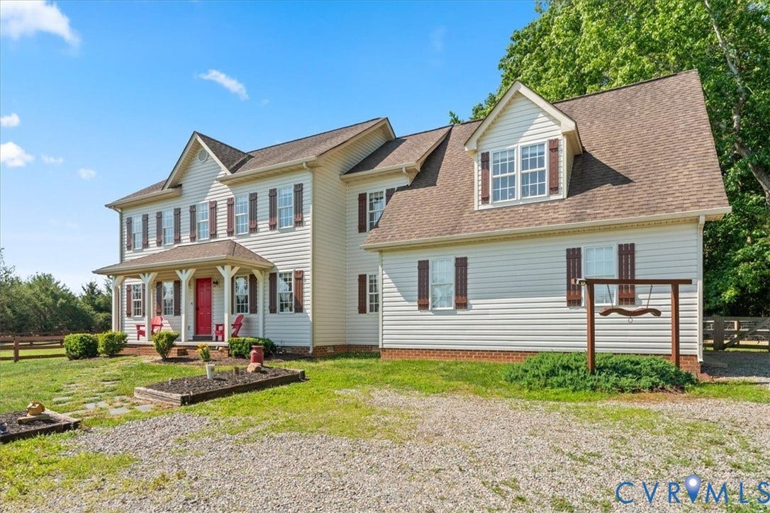 Traditional-style residence featuring light-colored siding and a covered front porch with a vibrant red entry door