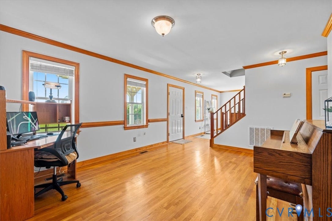 Bright, open-concept room featuring wood-finish flooring, white walls, and warm wood trim