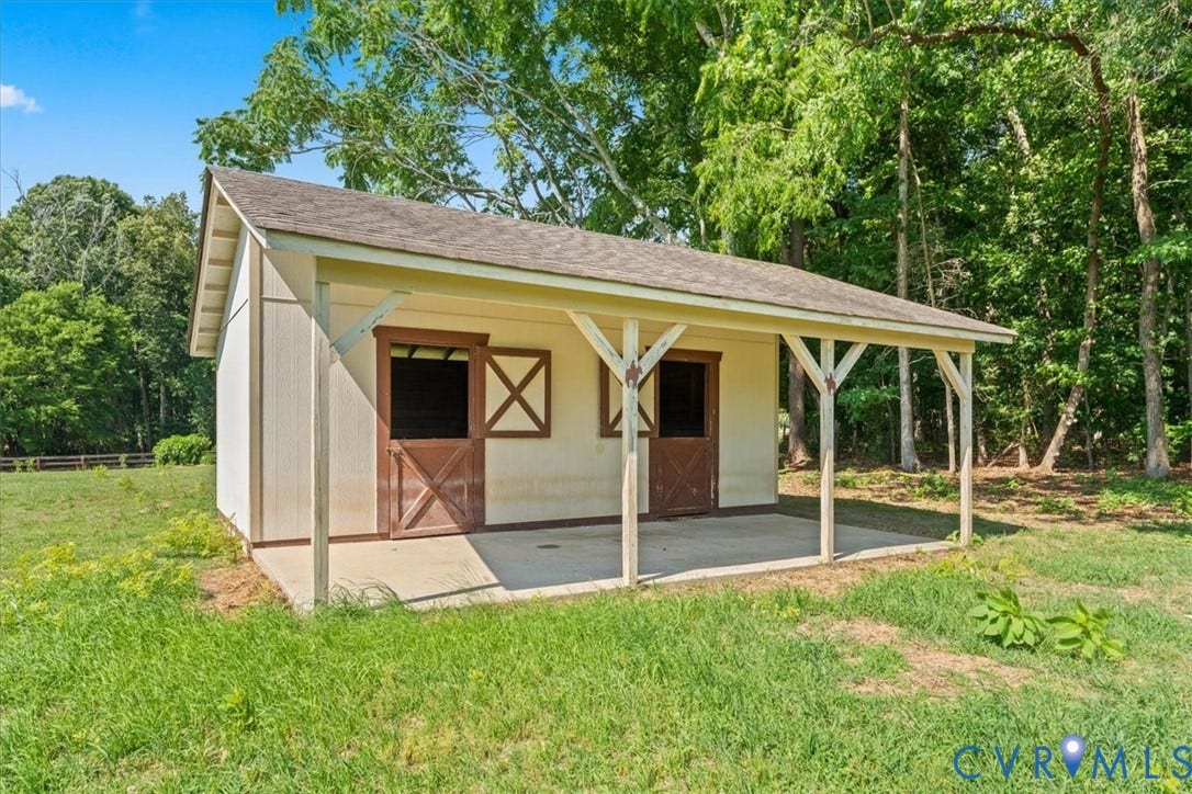 Utility building featuring a covered porch, two barn-style doors, and a neutral exterior finish