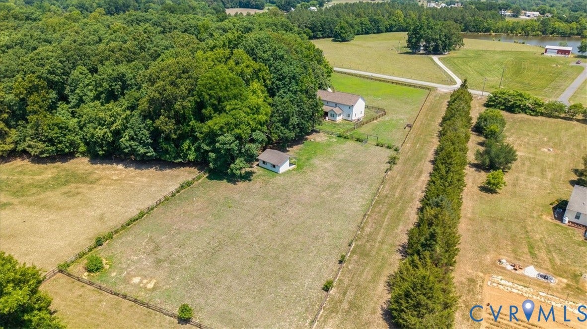 Expansive property featuring a main residence, an outbuilding, fenced pasture areas, mature tree lines, and a backdrop of dense woodland