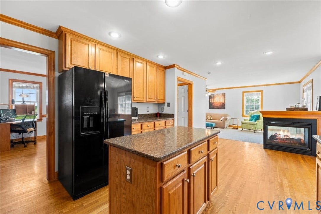 Spacious kitchen featuring extensive wood cabinetry, granite-style countertops, wood-finish flooring, a central island, and recessed lighting