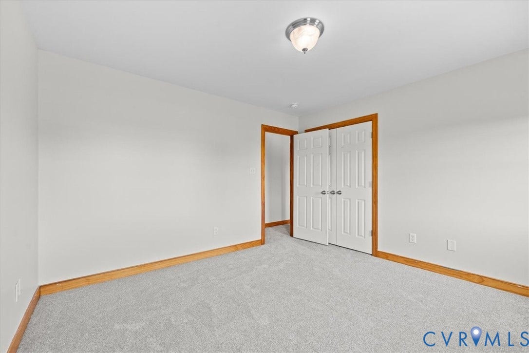 Bright interior space featuring two windows with wood-trim framing, light carpeting, and a flush-mount ceiling light fixture