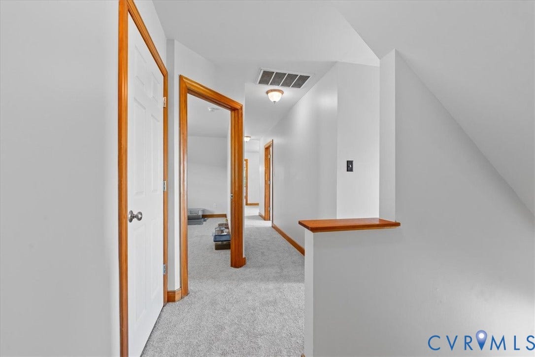 Staircase featuring wood railings and newel posts with carpeted treads