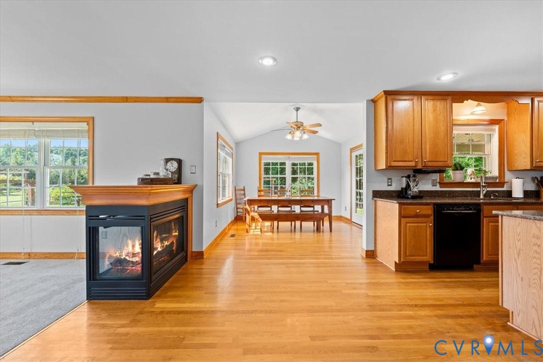 Open-concept interior featuring wood-finish flooring throughout, a two-sided fireplace, and recessed lighting