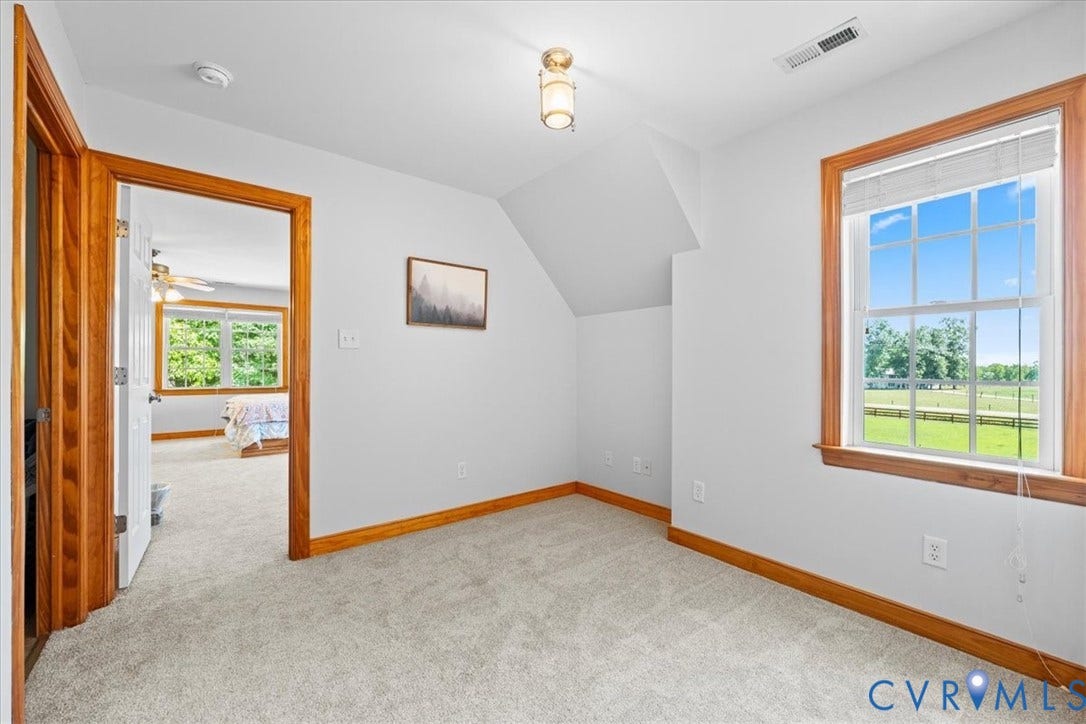 Bathroom featuring a window with natural wood trim, white toilet, and a patterned shower curtain