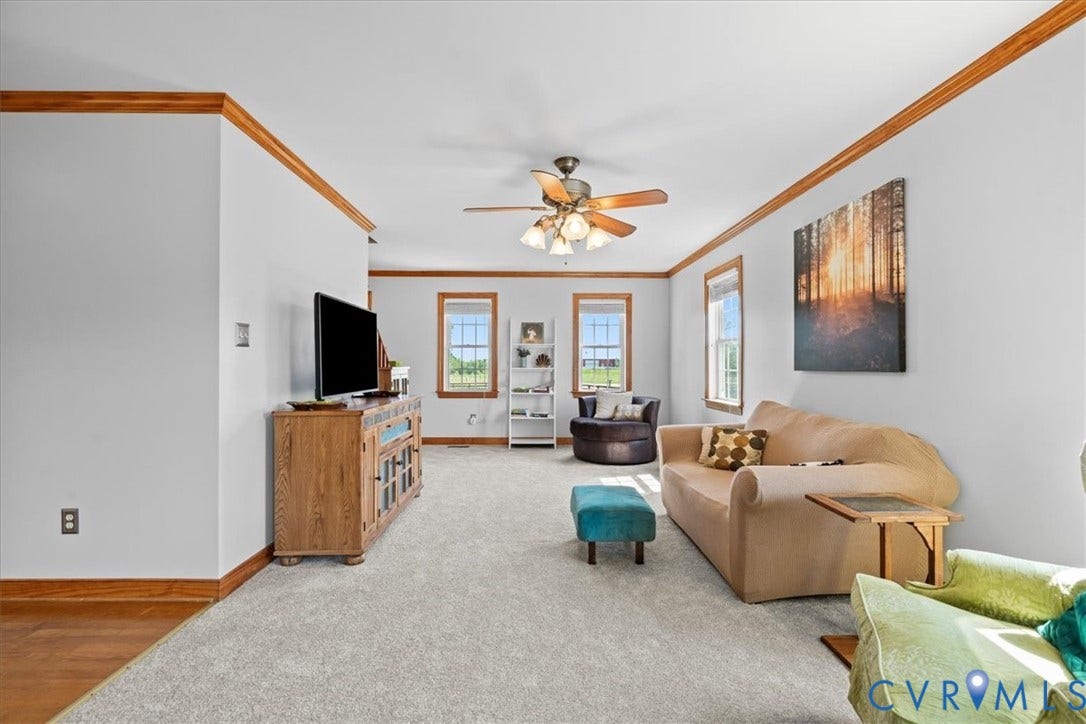 Hardwood-style flooring throughout a spacious room featuring a wooden staircase, white walls, and wood trim