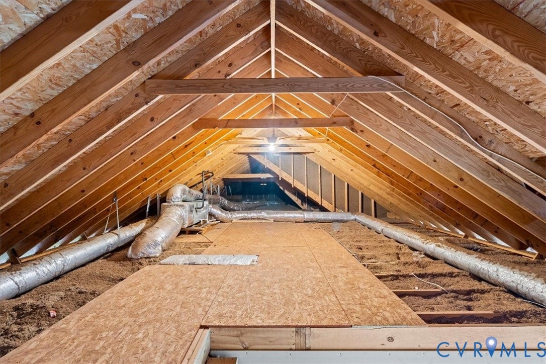 Expansive attic space featuring exposed wood rafter construction, partial plywood flooring, and visible ductwork