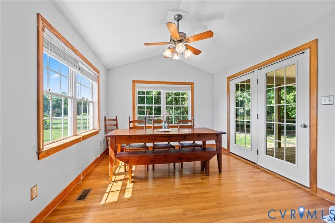 Dining area featuring light wood-finish flooring, white walls, and a vaulted ceiling