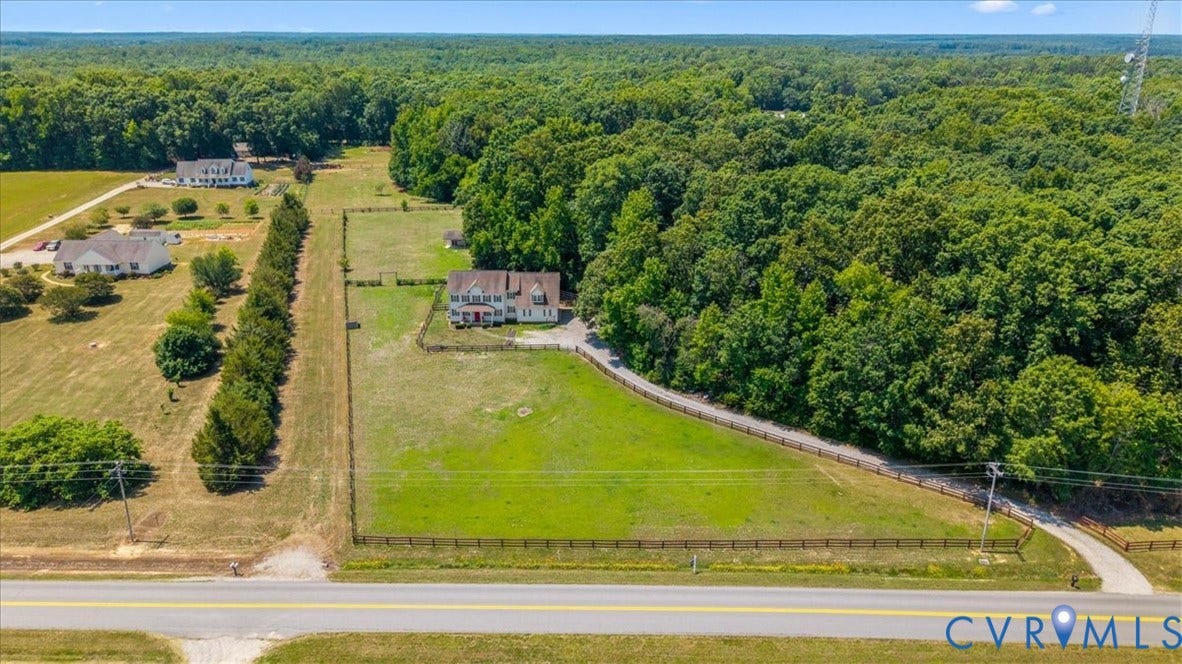 Extensive acreage featuring a primary residence, a substantial grassy field, and a perimeter fence