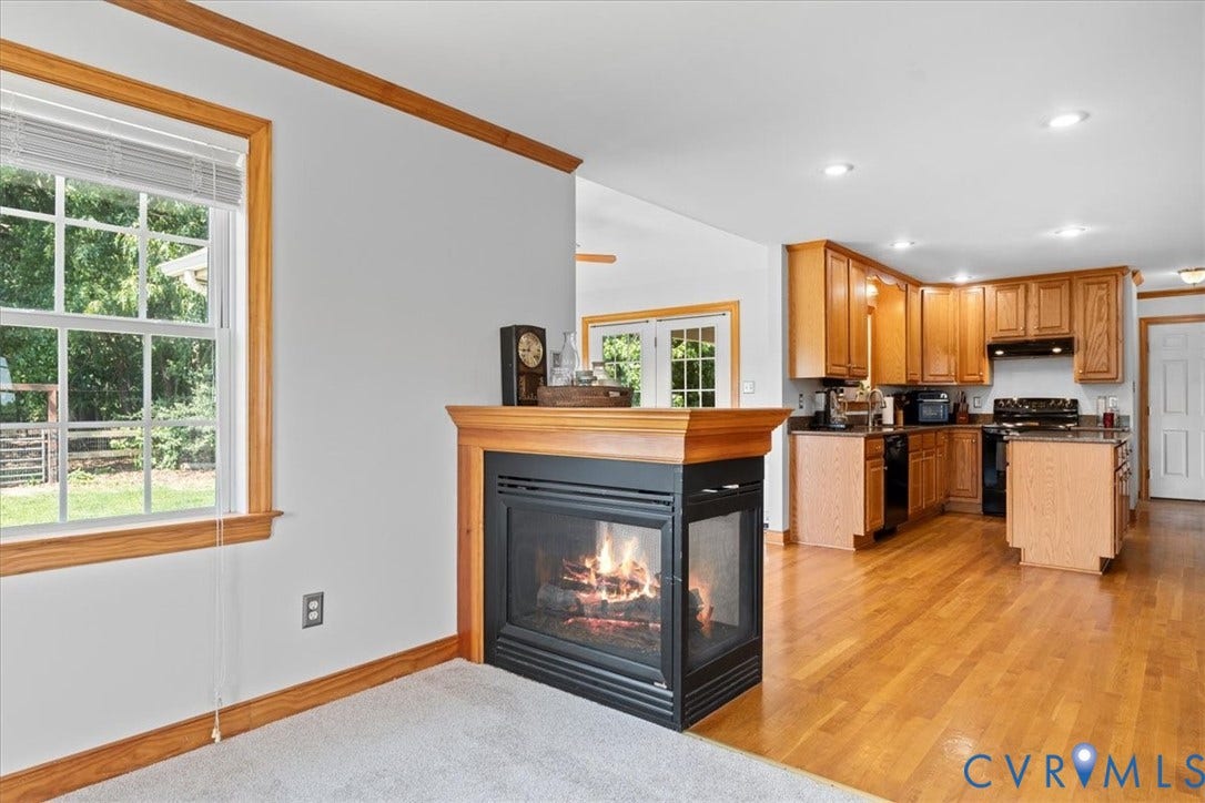 Carpeted living area featuring light-toned walls, wood-finish trim, and a ceiling fan with integrated lighting