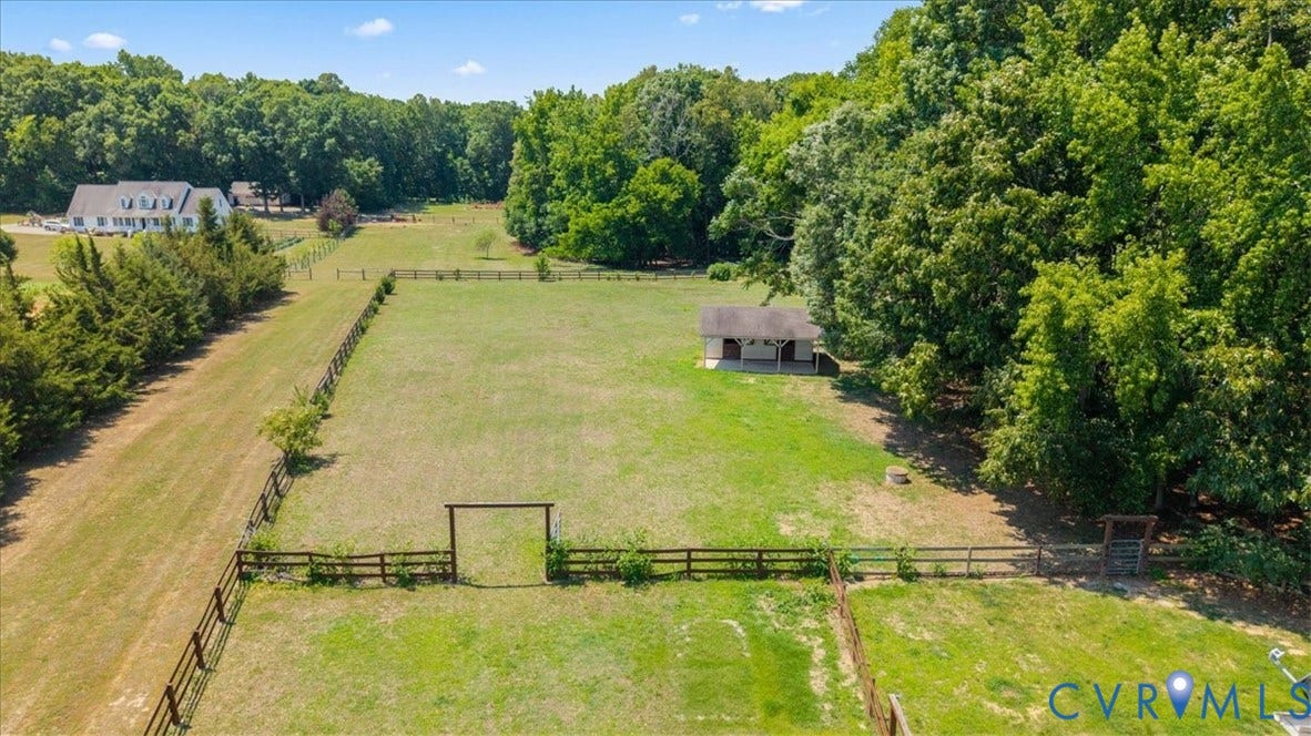 Expansive green pastures featuring perimeter fencing, a wooden gate, and a shed structure