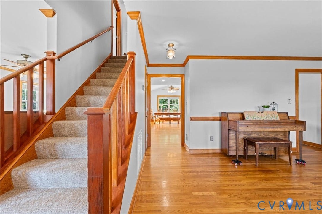 Hardwood flooring throughout the entry, complemented by a carpeted staircase with wood banisters and railings