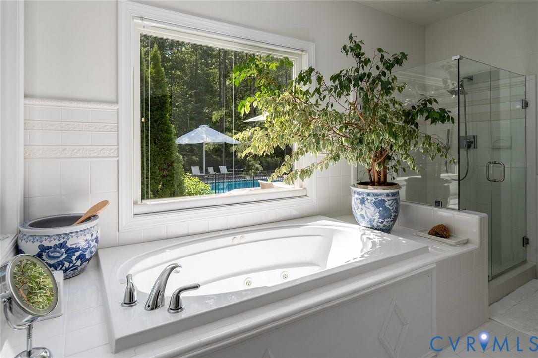 3124 Rock Cress Lane, Mill Forest, Sandy Hook, VA 23153 Two large windows bring in natural light in the Primary Bath. A large glass stall shower adds to the reflective surfaces in this white on white space; tile wainscoting adds texture.