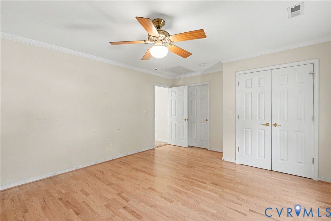 Room featuring wood-finish flooring, white walls, and a ceiling fan with light fixture