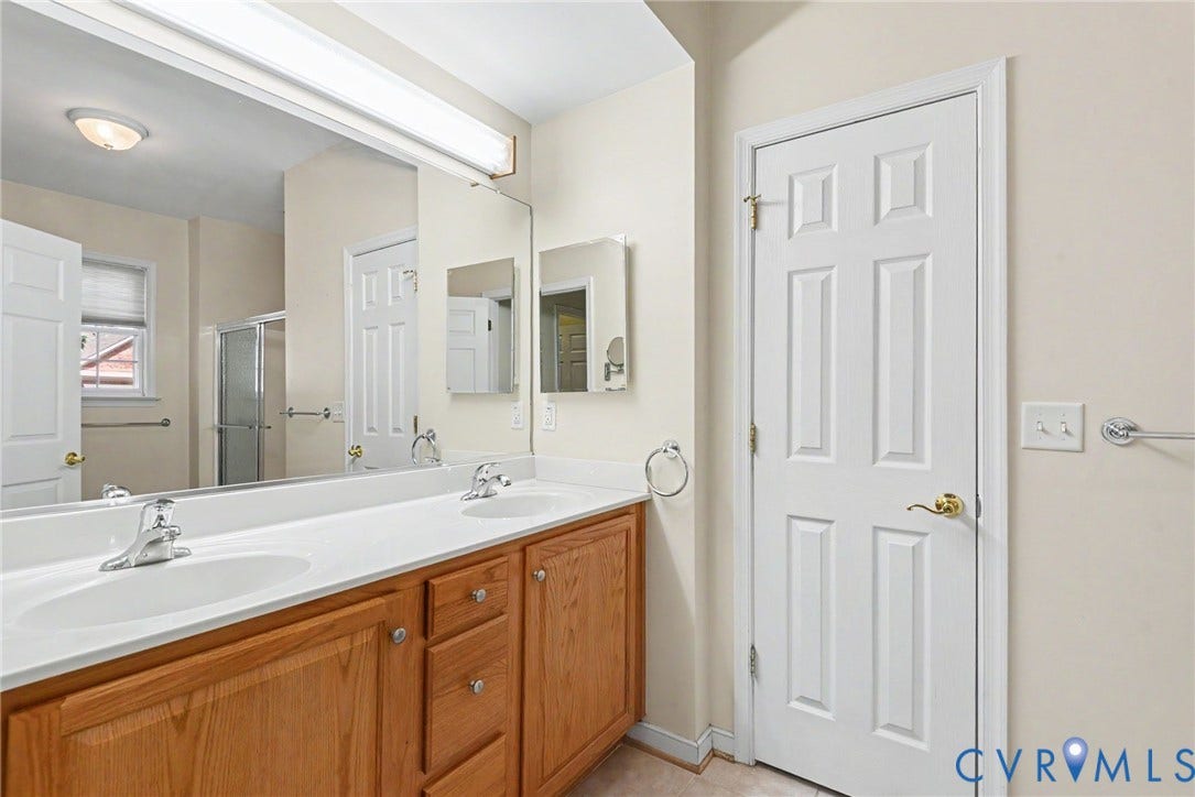 Double vanity featuring dual sinks, ample counter space, and wood-finish cabinetry