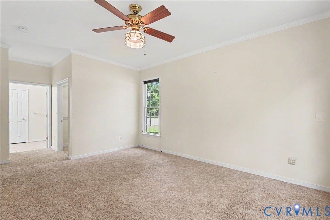 Spacious room featuring neutral carpet flooring, light-toned walls, and white crown molding