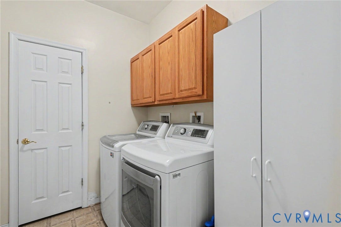 Dedicated laundry space featuring overhead wood-finish cabinetry, a tall white storage cabinet, and neutral-toned wall paint