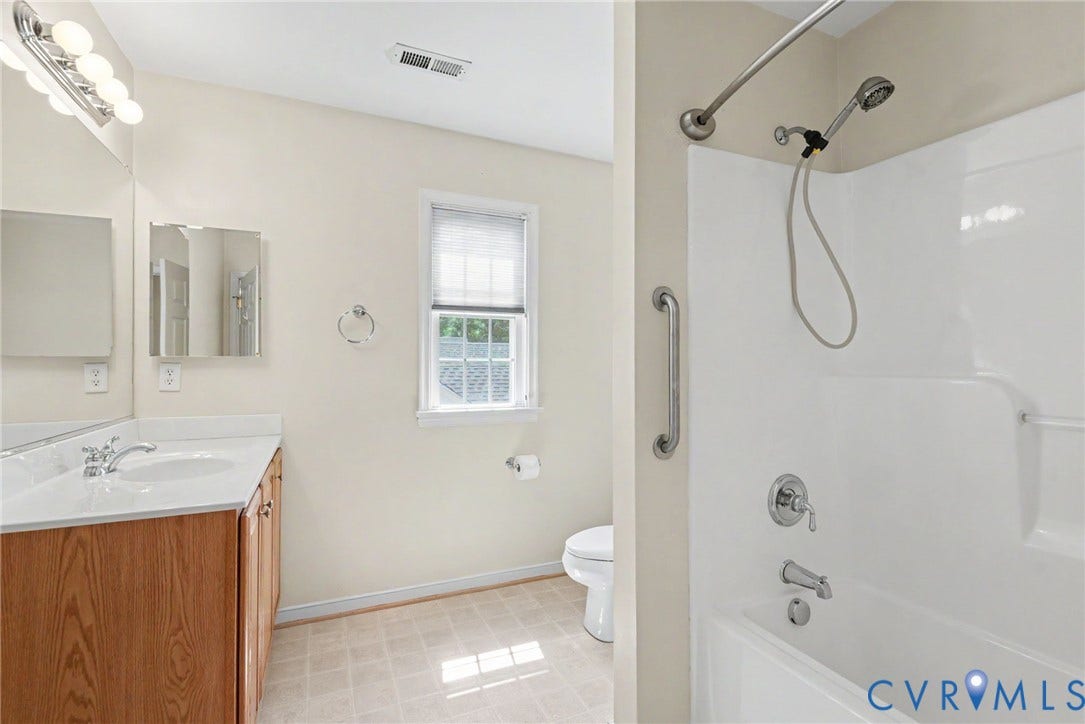 Bathroom with a wood-finish vanity, white countertop, and integrated sink