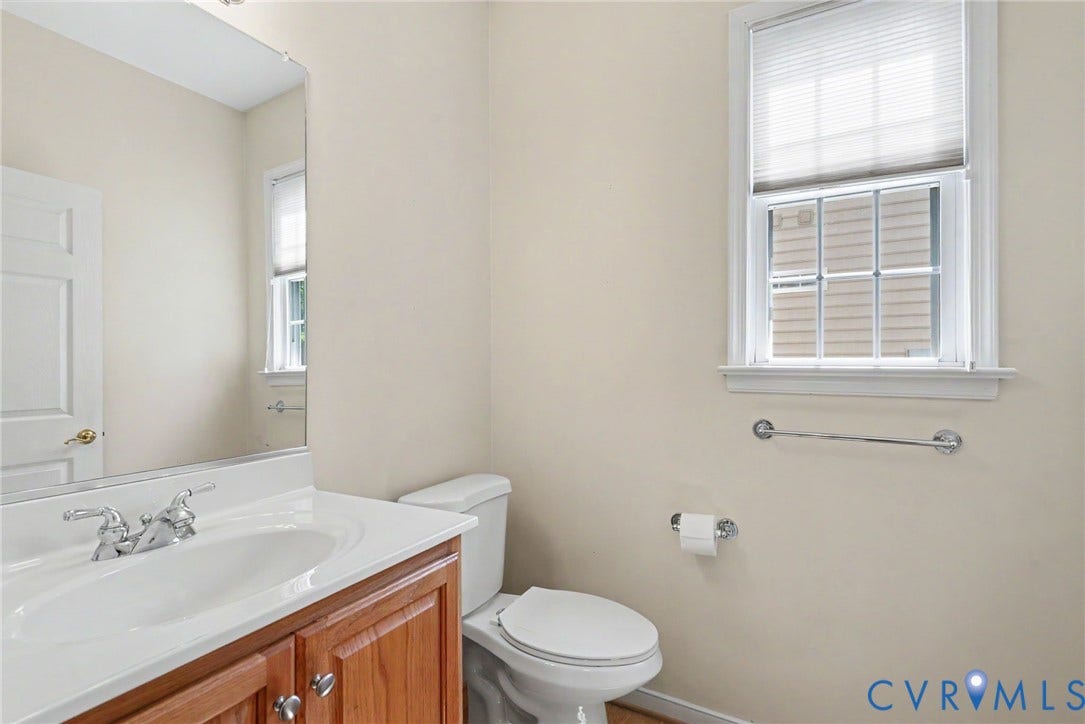Bathroom featuring a single vanity with wood-finish cabinetry, a white countertop, and an undermount sink with chrome fixtures