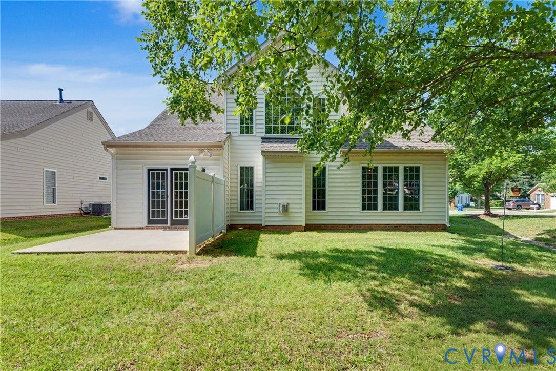 Rear exterior featuring white vinyl siding, a concrete patio, and a double-door entry