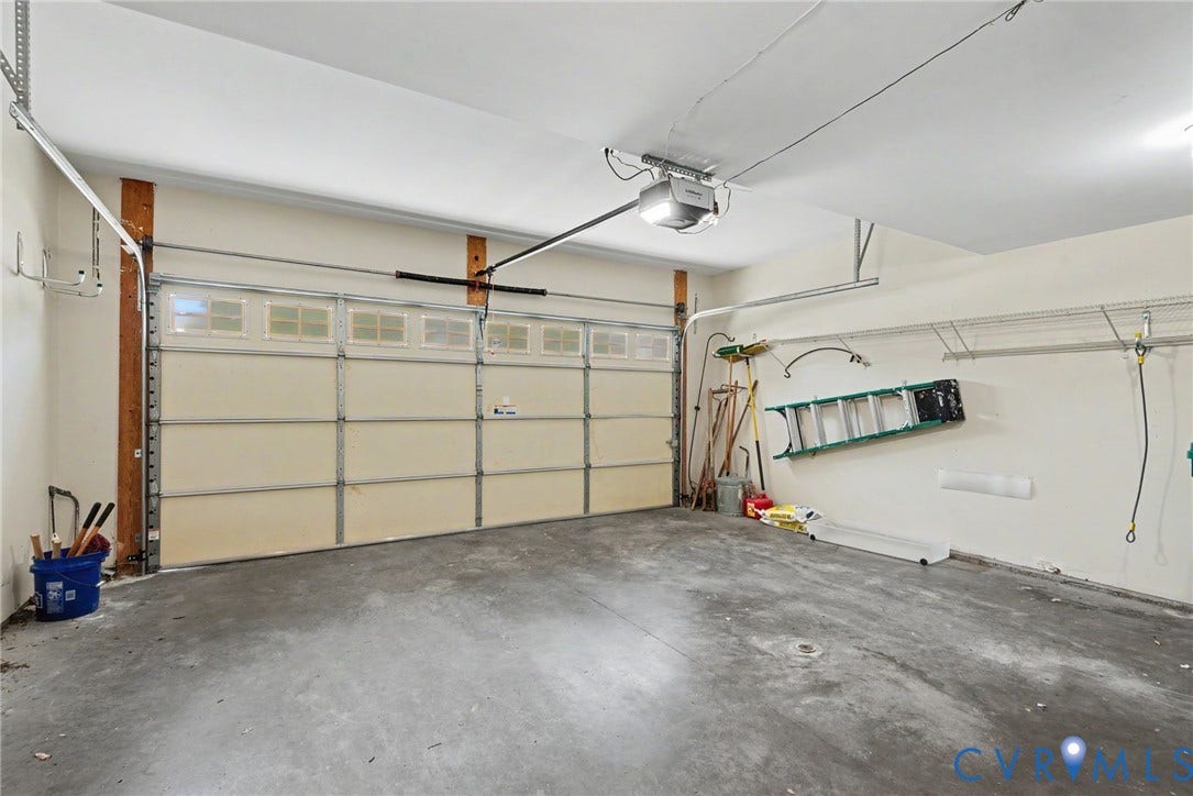 Spacious garage featuring a paneled overhead door with frosted window panels, an automatic garage door opener, concrete flooring, and interior wall shelving