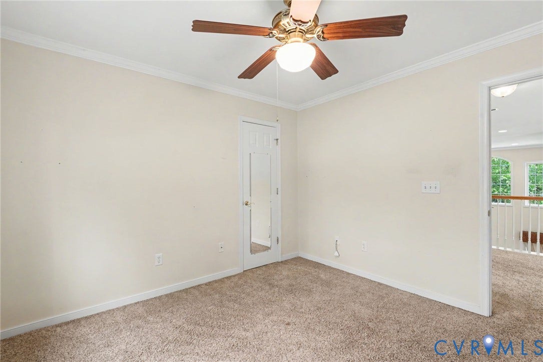 Carpeted room with a ceiling fan featuring wood-finish blades and a central light fixture