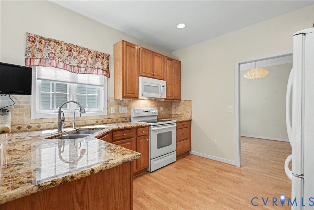 Kitchen featuring wood cabinetry, light-toned granite countertops, and a tile backsplash