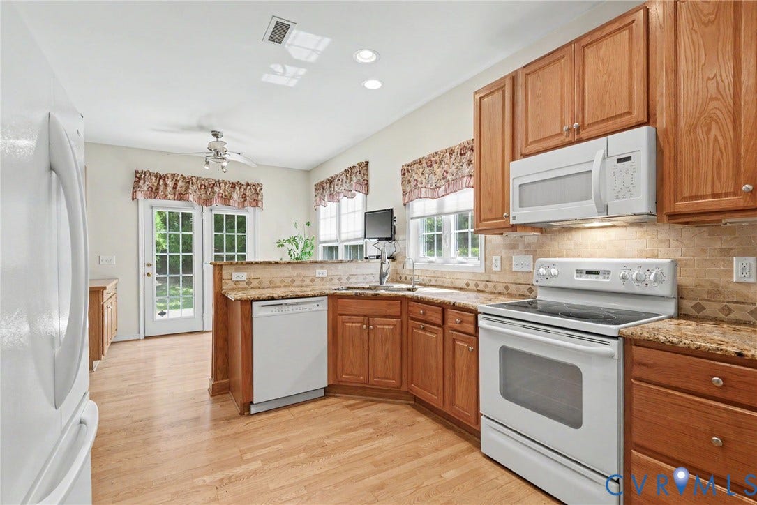 Kitchen featuring wood-finish flooring, wood cabinetry, granite countertops, and a tile backsplash