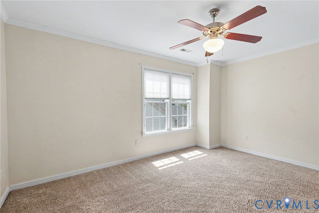 Carpeted room featuring a ceiling fan with light fixture, double window with blinds, and crown molding