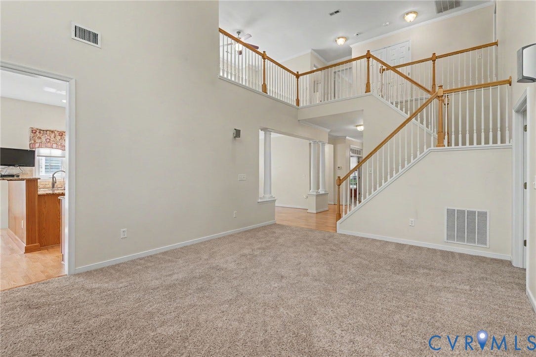 Two-story foyer with carpeted flooring, a grand staircase featuring wood handrails and white balusters, and recessed lighting