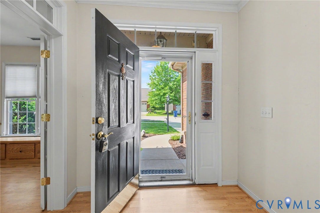 Front entry featuring a solid paneled door, sidelight, and transom window