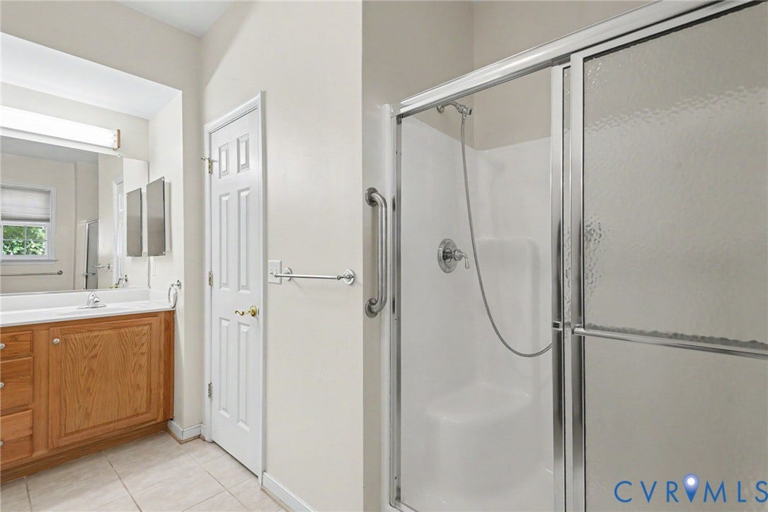Bathroom featuring a walk-in shower with a built-in seat, glass enclosure, and grab bar