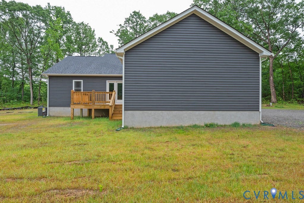 9256 Fredericks Hall Road, Con Creek, Mineral, VA 23117 Rear exterior with gray horizontal siding, a wooden deck with steps, and a dark shingle roof