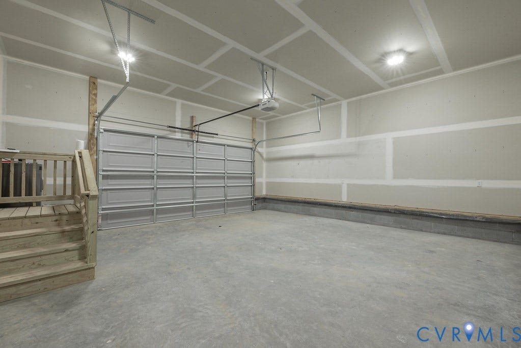 9256 Fredericks Hall Road, Con Creek, Mineral, VA 23117 Spacious garage featuring a concrete floor, unpainted drywall walls, a sectional garage door, a garage door opener, and overhead lighting