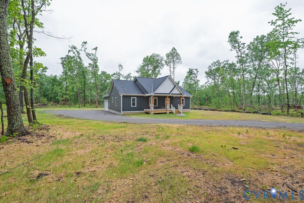 9256 Fredericks Hall Road, Con Creek, Mineral, VA 23117 Contemporary home featuring dark gray siding, a prominent gable roof, and a covered front porch with natural wood columns