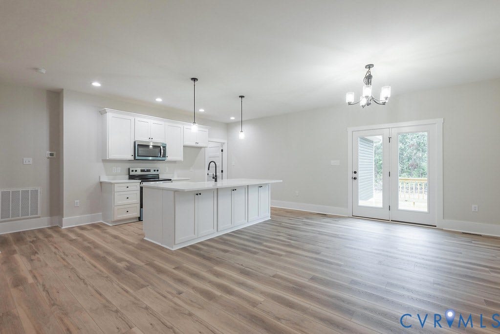 9256 Fredericks Hall Road, Con Creek, Mineral, VA 23117 Open-concept kitchen featuring white shaker cabinetry, an island with countertop seating, and stainless steel appliances
