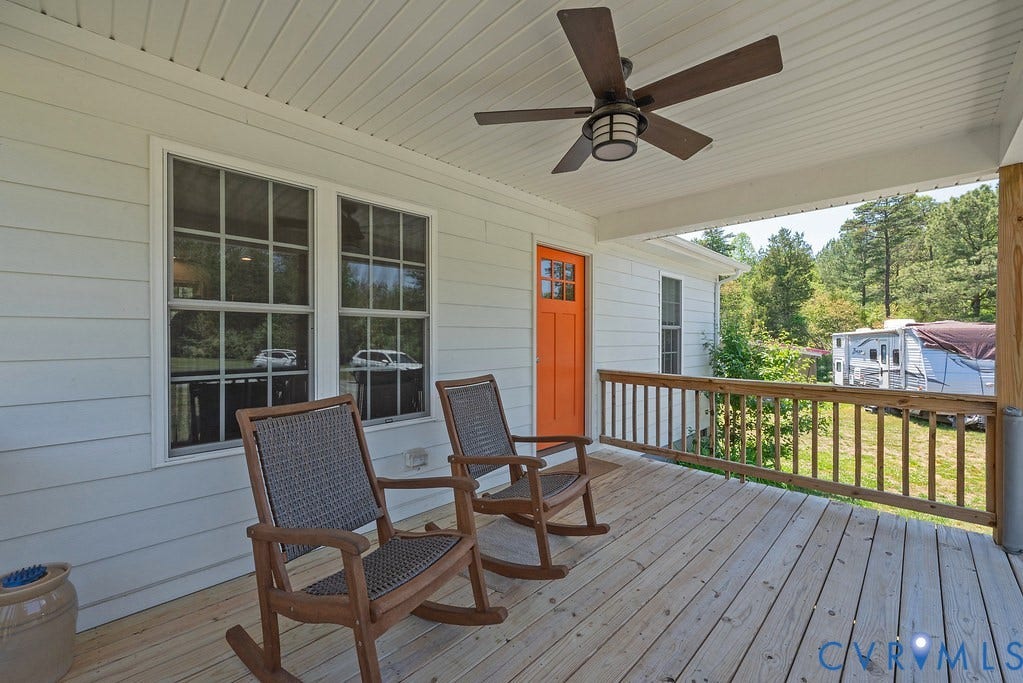 4336 Hells Bend Road, Quiet And Private, Palmyra, VA 22963 Covered front porch featuring a wood-finish floor, white siding, a vibrant orange entry door with glass panels, and an outdoor ceiling fan with integrated lighting