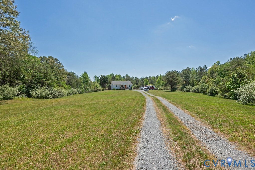 4336 Hells Bend Road, Quiet And Private, Palmyra, VA 22963 Gravel driveway leading to a white residence with an orange front door, set amidst expansive green lawns and mature trees