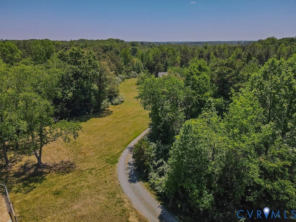 4336 Hells Bend Road, Quiet And Private, Palmyra, VA 22963 Expansive property featuring a winding gravel driveway, mature trees, open grassy areas, and a distant structure nestled within the foliage